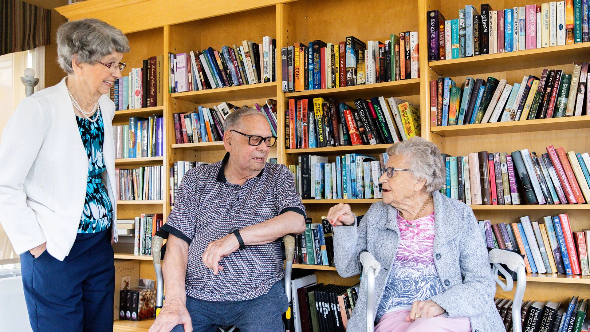 A group of senior citizens taking with each other in small library on site